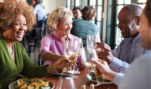 Group Of Smiling Senior Friends Meeting For Meal In Restaurant