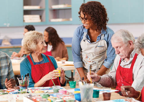 Group Of Retired Seniors Attending Art Class In Community Centre With Teacher
